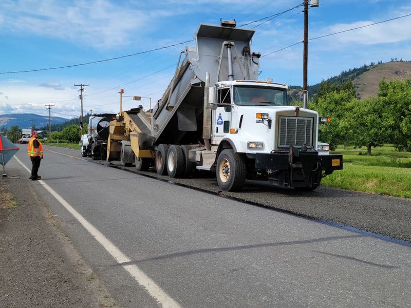 Paving crew with dump truck laying asphalt on a rural Oregon Coast road