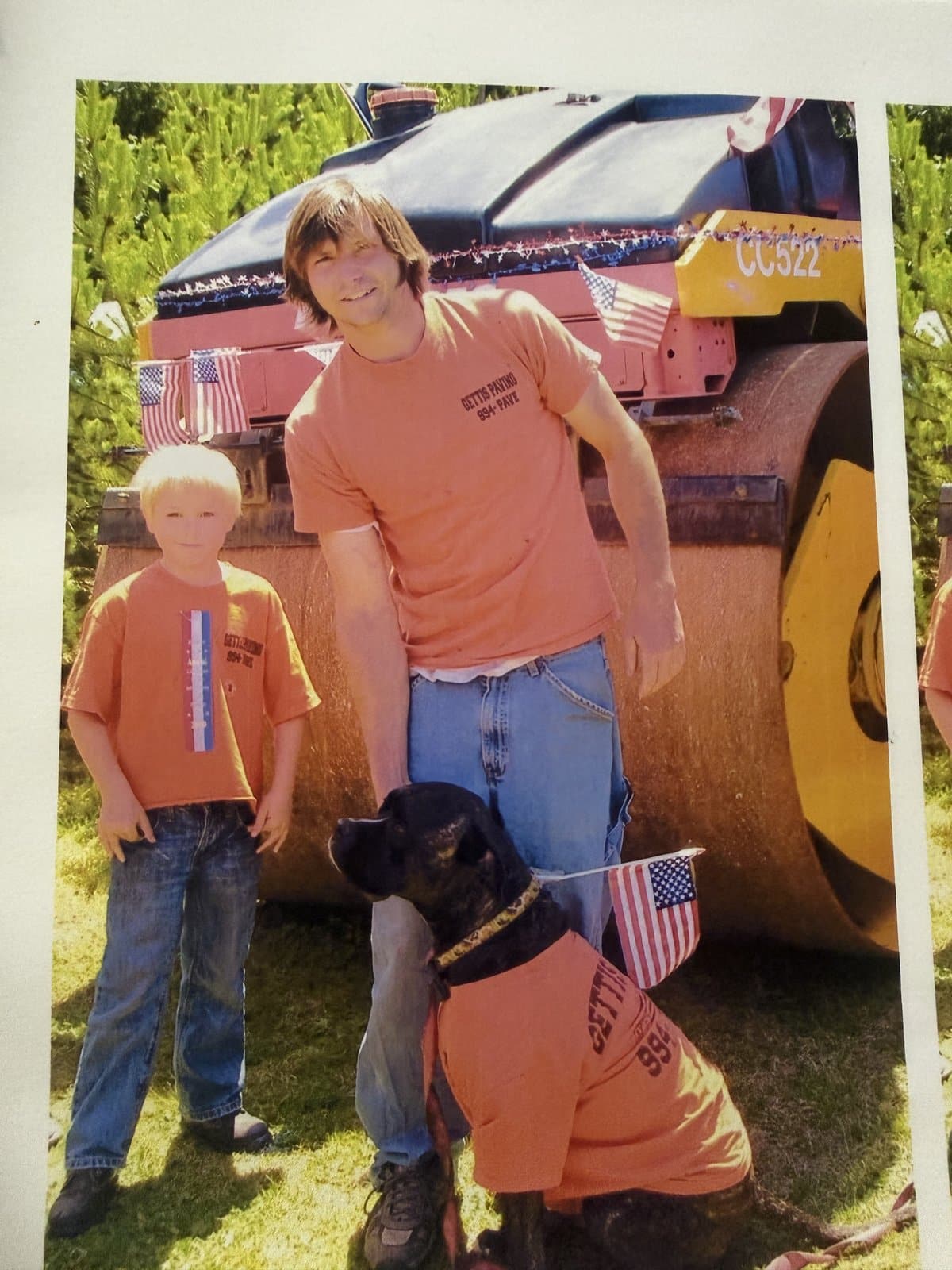 Father and son in Gettis Paving shirts with the family dog